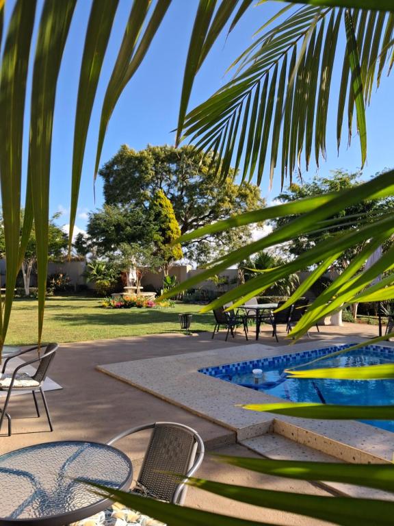 a resort with a pool and chairs and palm trees at The Ridge BnB in Manzini