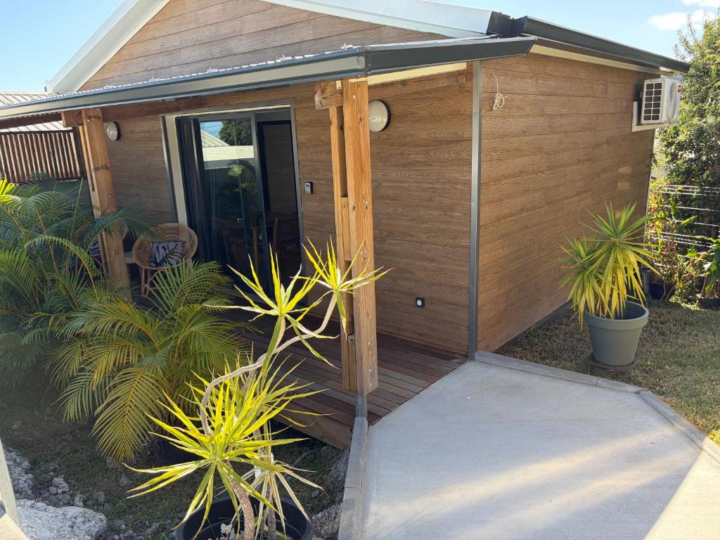 a wooden cabin with a door and some plants at O coeur de l'ouest Bungalow Maloya in Le Bois de Nèfles