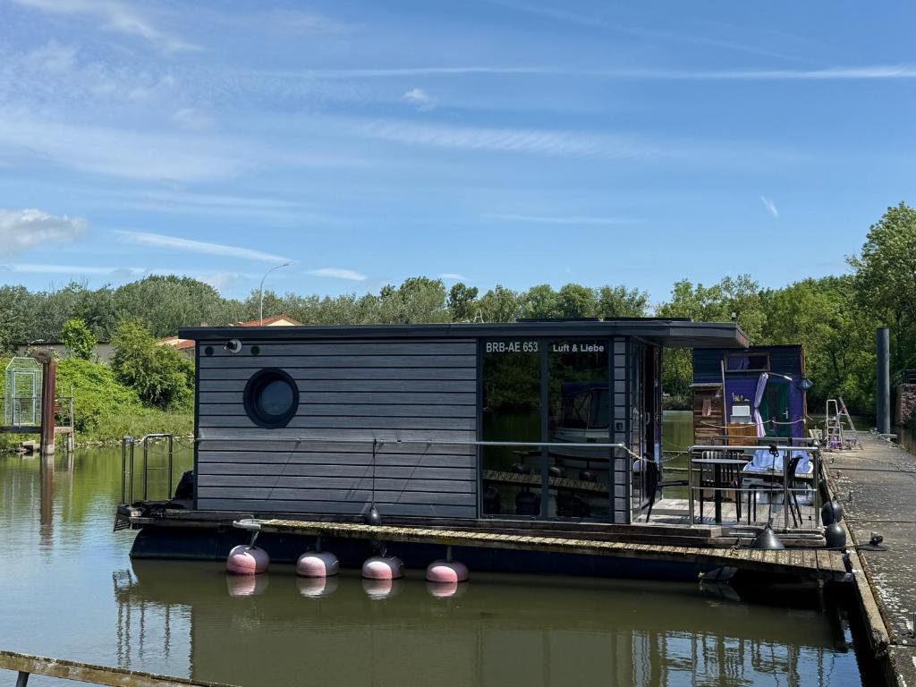 a small house on a dock on a body of water at Hausboot Luft & Liebe in Halle an der Saale