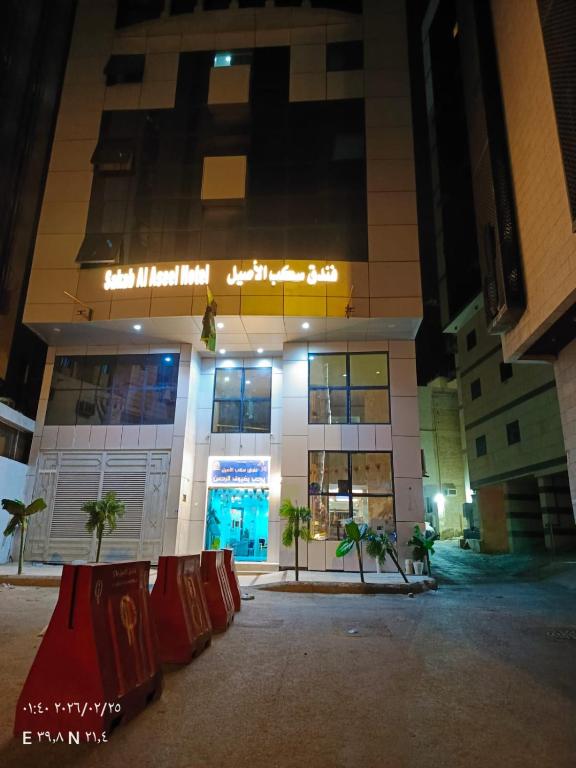 a building at night with palm trees in front of it at فندق سكب الأصيل in An Naqāʼ