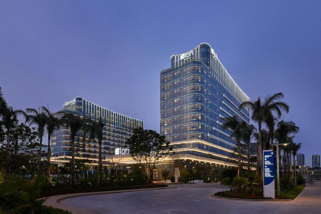 a large building with palm trees in front of it at Aloft by Marriott Xiamen Xiangan in Xiamen