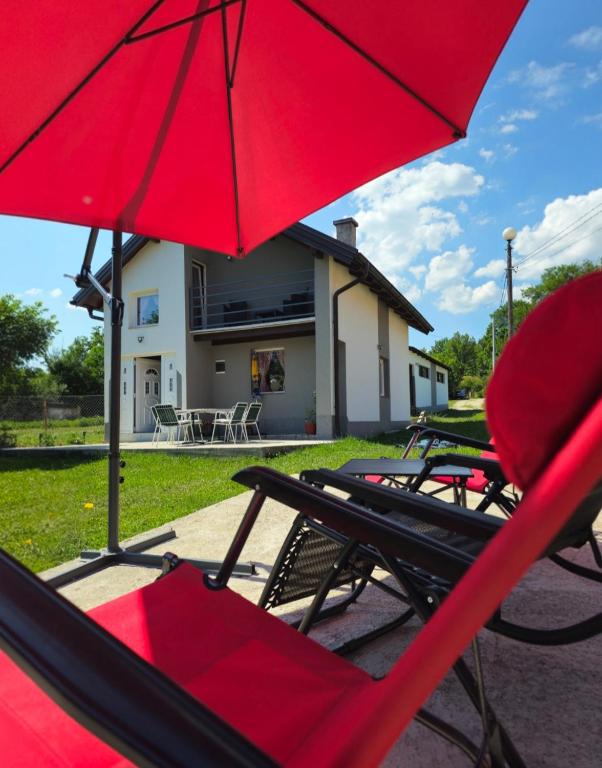 a group of lawn chairs and a red umbrella at Vikendica Stanković in Šipovo