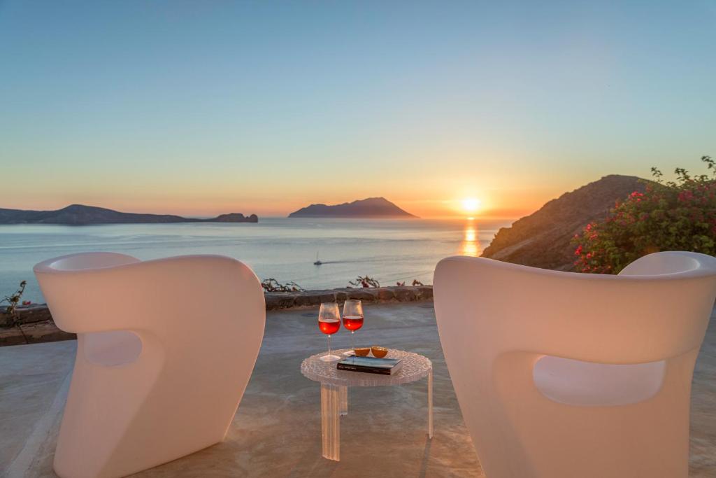 a table with two glasses of wine on the beach at sunset at Sunset Flower Villa in Kástron