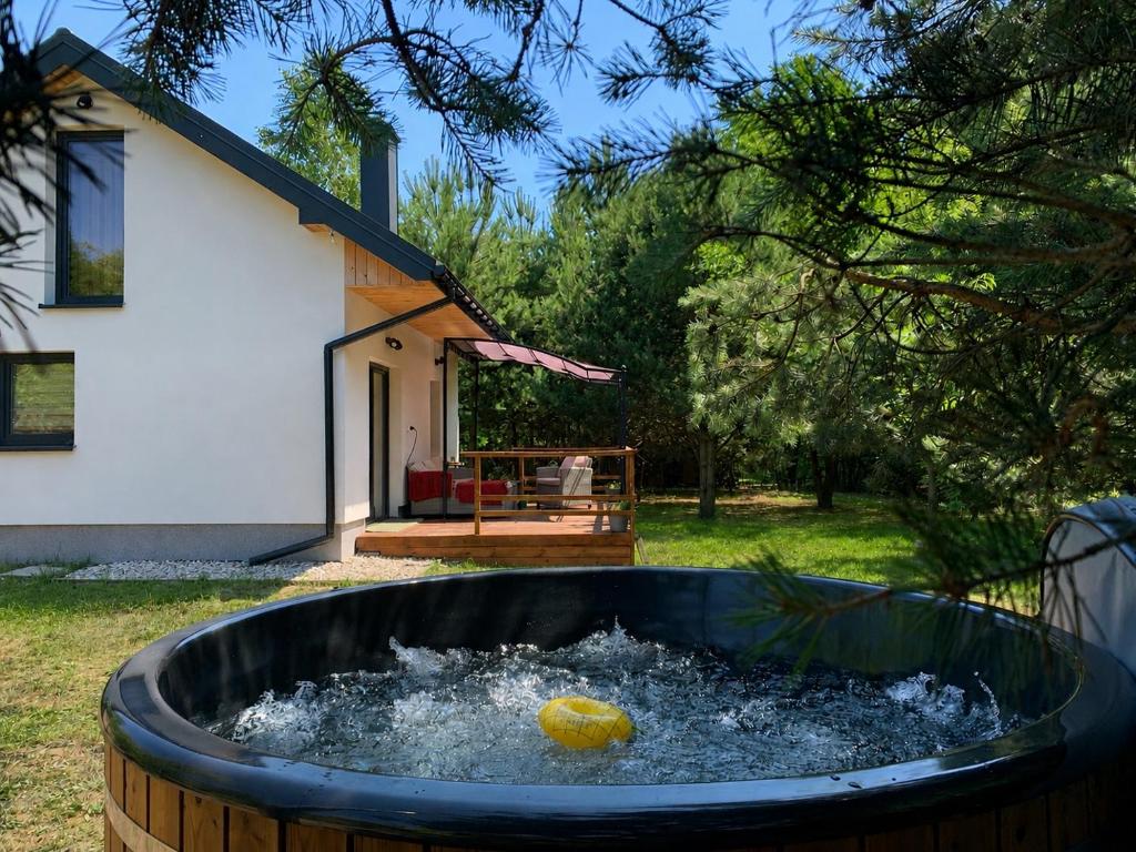 a pool of water with a ball in it in front of a house at Domek Wśród Pól z Balia Jacuzzi in Rawa