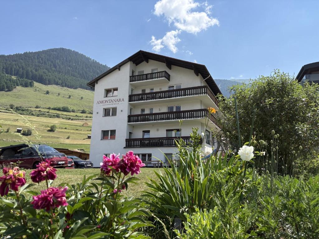 a white building with balconies and flowers in a field at Amontanara in Nauders