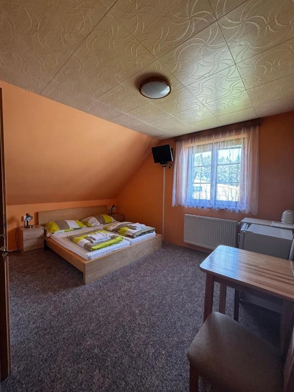 a bedroom with two beds and a table and a window at Penzion U Horejšů, Zadov - Churáňov in Stachy