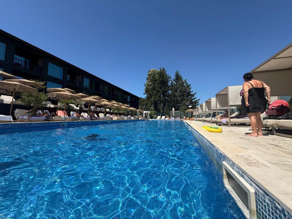 a man is standing next to a swimming pool at Мия 2 Deluxe Royal Spa in Velingrad