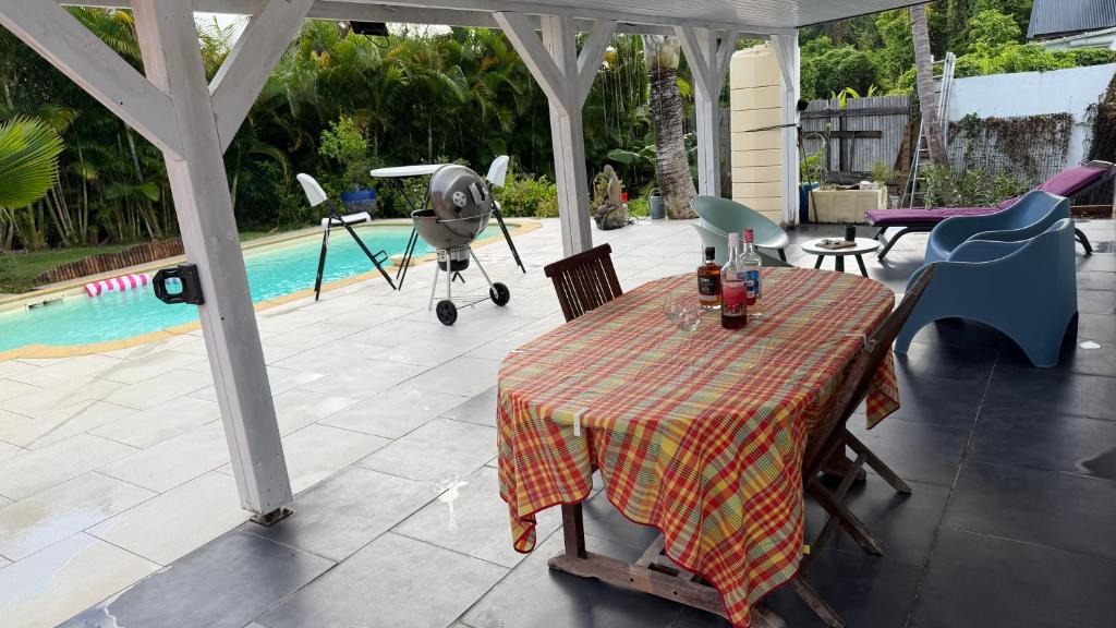 a covered patio with a table and a pool at Studio piscine centre Gosier in Le Gosier