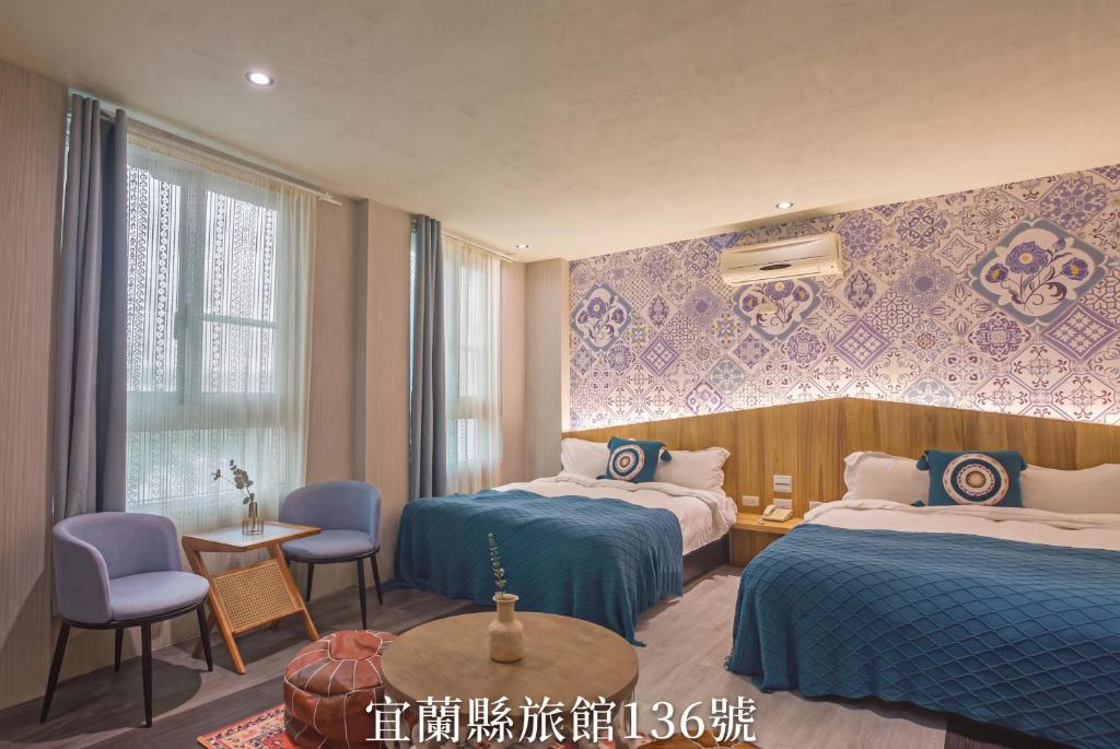 a hotel room with two beds and a table and chairs at Ashare Hotel in Jiaoxi
