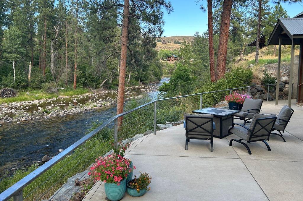 a patio with a table and chairs next to a river at River Pines Inn in Winthrop