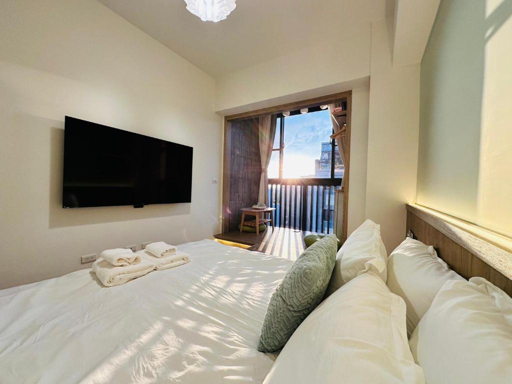a bedroom with a white bed with a flat screen tv at mini嵐輕旅 in Guanyin