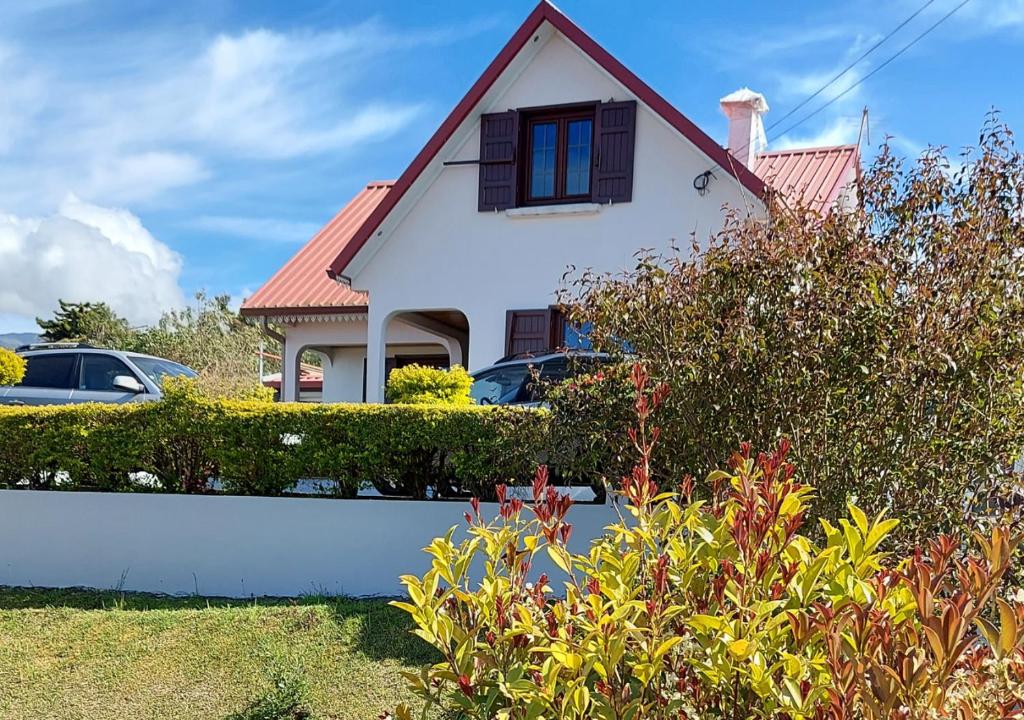 a white house with a red roof and some bushes at Ilodays in La Plaine des Cafres