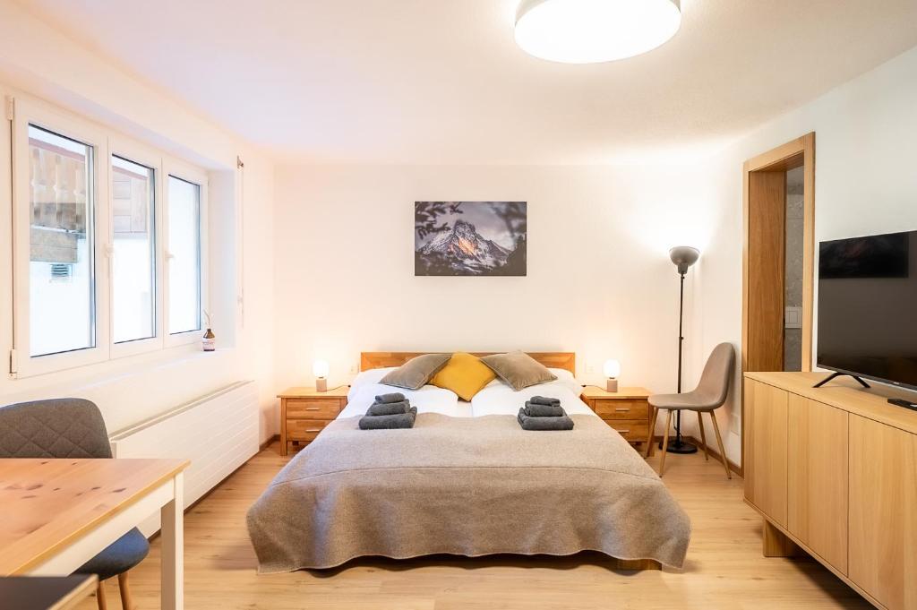 a bedroom with a bed and a flat screen tv at Studio Omis in Zermatt
