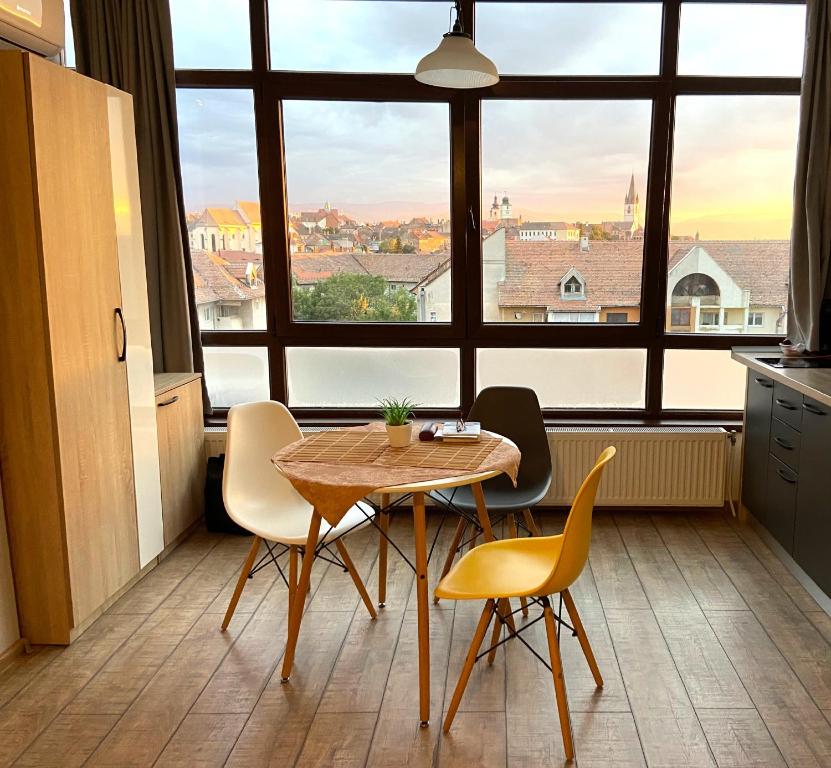a table and chairs in a room with a large window at Panorama studio in Sibiu