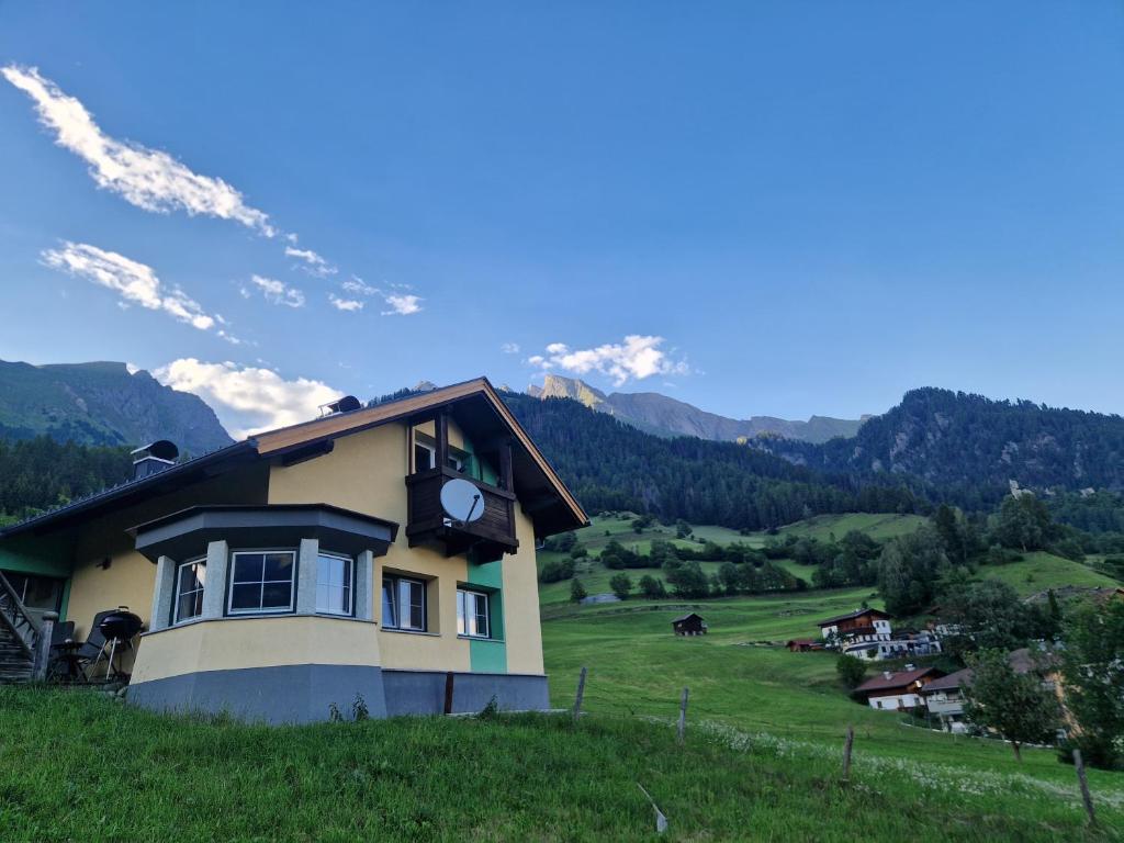 a house on a hill with mountains in the background at Das Steinmetzhäuschen in Virgen