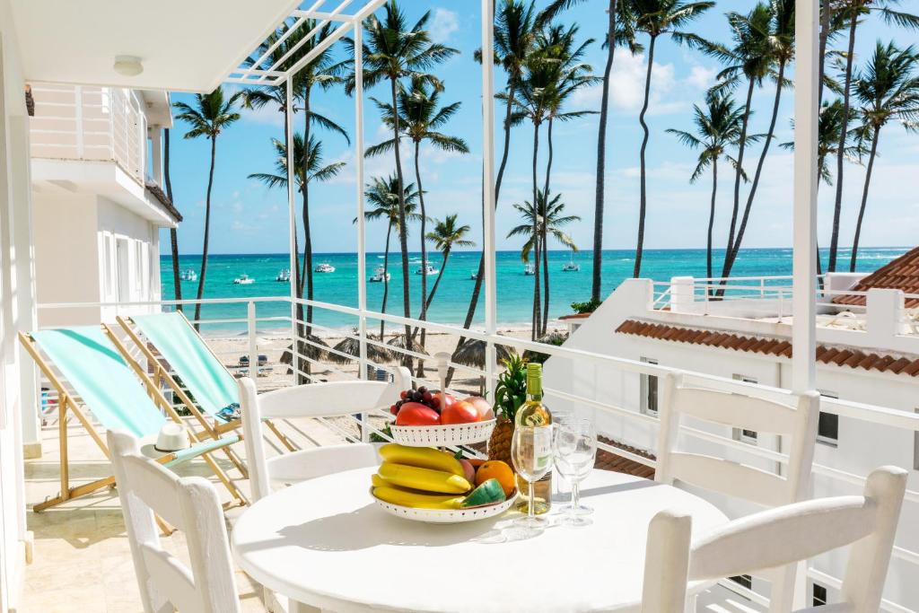 a table with fruit on a balcony overlooking the ocean at FIESTA LOS CORALES - VILLAS and SUITES in Punta Cana