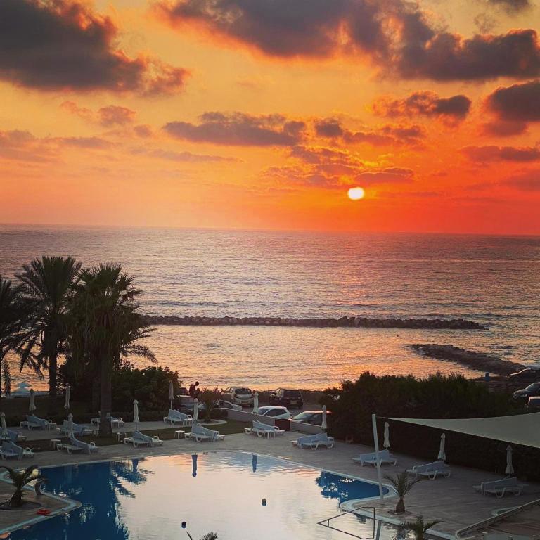 a sunset over the ocean with a swimming pool at Venus Beach Hotel in Paphos