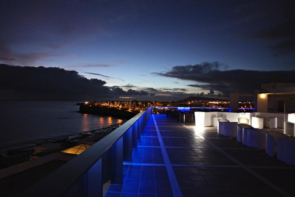 a balcony with blue lights on the water at night at Sandos Papagayo in Playa Blanca