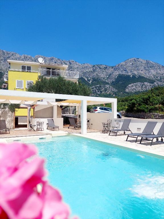 a swimming pool with chairs and a house at Apartments Dia in Zaostrog