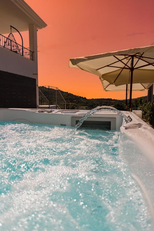 a pool with an umbrella and a swimming pool at DOMO MARE E TERRA Boutique Rooms and Spa in Posada