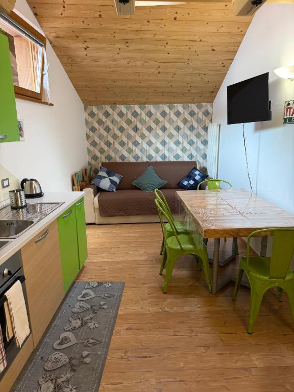 a kitchen and living room with a table and a couch at Casa Seler - Appartamento verde in Predazzo