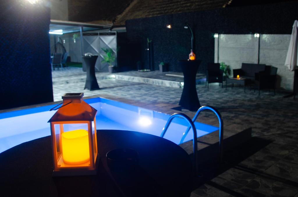 a lantern sitting on a table next to a pool at night at Apartman Crvenka bazen in Crvenka
