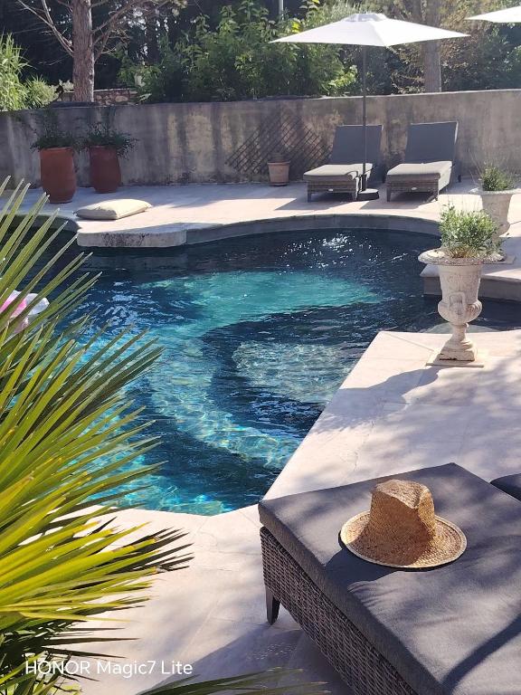 a swimming pool with a hat sitting on a table at Le Mas Paolo in Le Thor