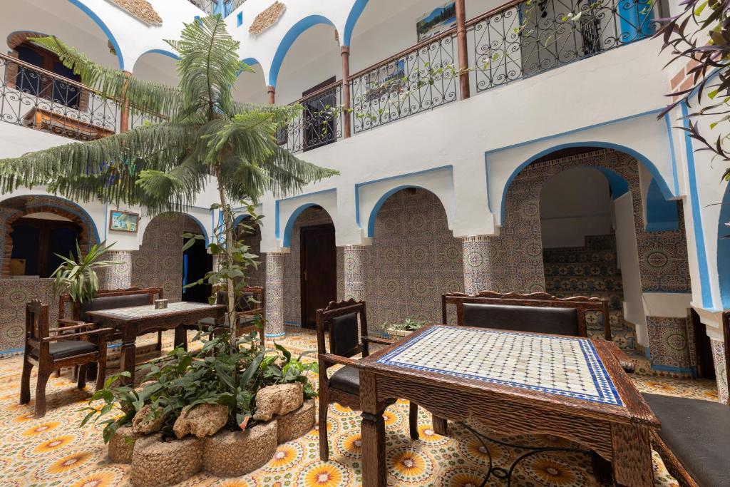 a courtyard with tables and chairs in a building at Hotel Nisrine in Chefchaouen