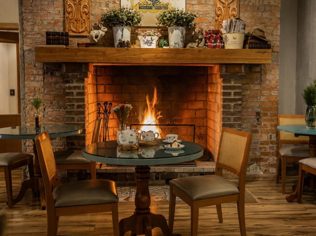 a fireplace in a restaurant with a table and chairs at Hotel Britanico Express in Gramado