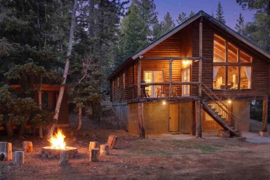 a log cabin with a fire in front of it at Rustic Mountain Log Cabin with Fire Pit in Duck Creek Village