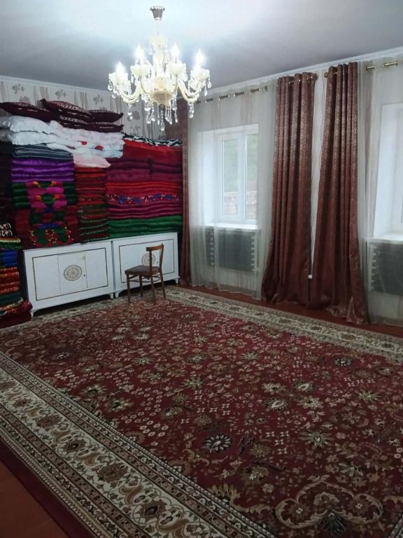 a living room with a chandelier and a red rug at OMKA Guest House in Toktogul