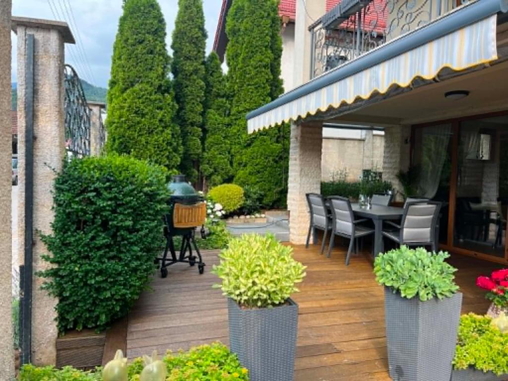 a patio with a table and chairs and plants at U Izhu with Private Pool, Sauna & BBQ in Prevala
