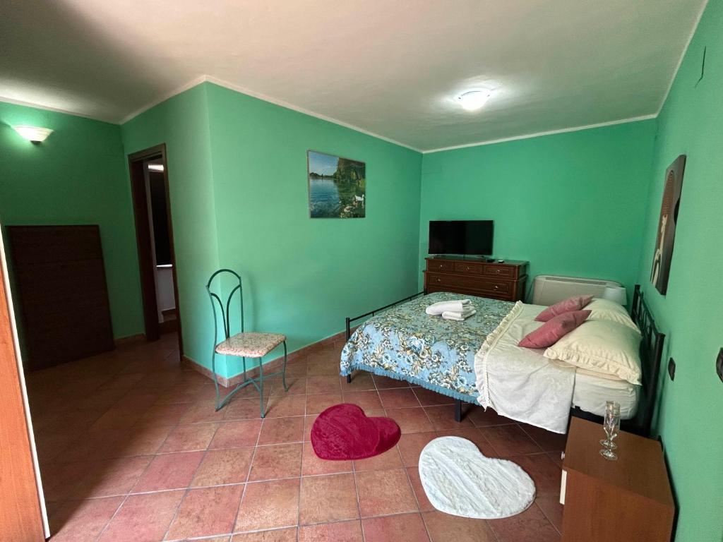 a bedroom with green walls and a bed and a chair at Casa Lory in Posta Fibreno
