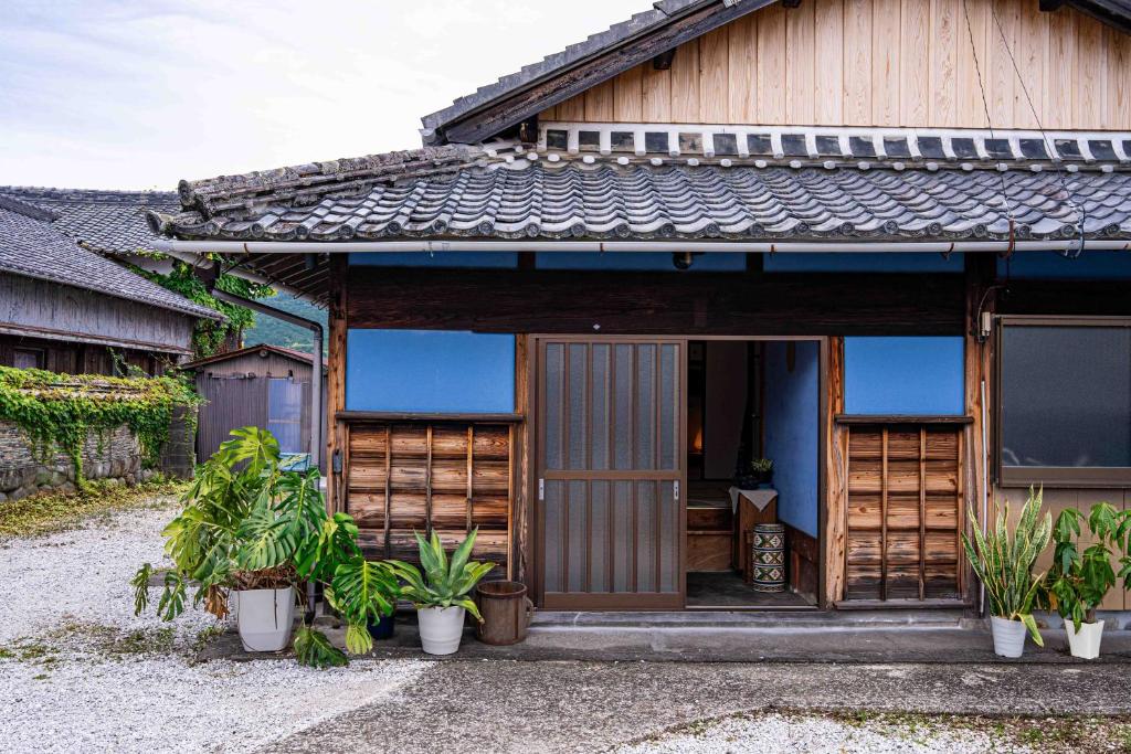 a wooden house with plants in front of it at 錆と煤 sabitosusu INN-prema- in Aki