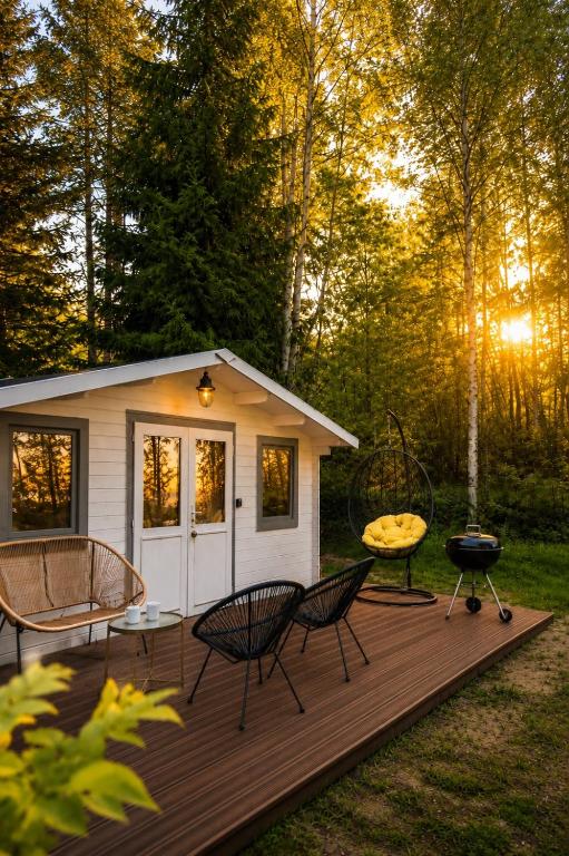 a cabin with a grill and chairs on a wooden deck at Baltic Beach Charm Tiny House C in Pērkone