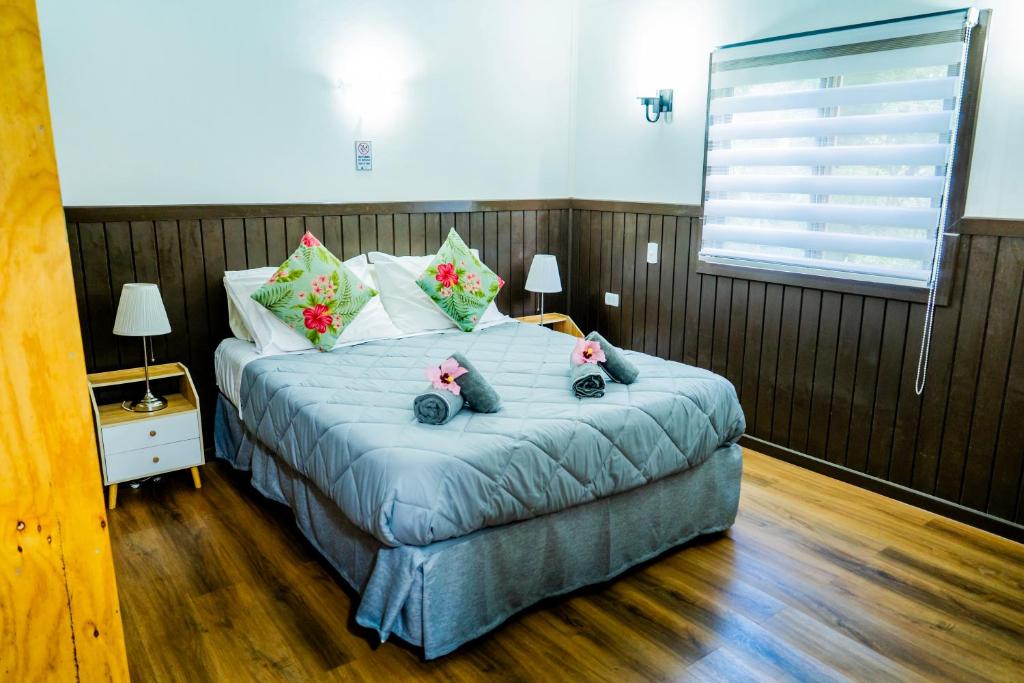 a bedroom with a bed with two stuffed animals on it at Cabañas Henua Iti in Hanga Roa