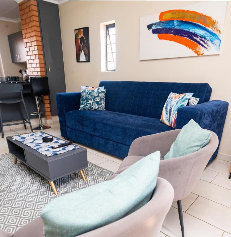 a living room with a blue couch and chairs at Modern 2 bedroom at Waterfall Ridge-Midrand in Midrand