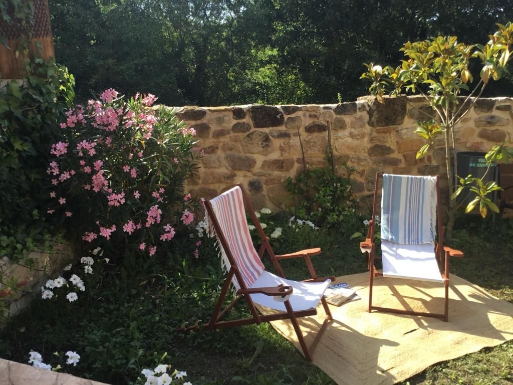 two chairs sitting in a yard next to a stone wall at Los acebos la suite in Gallejones