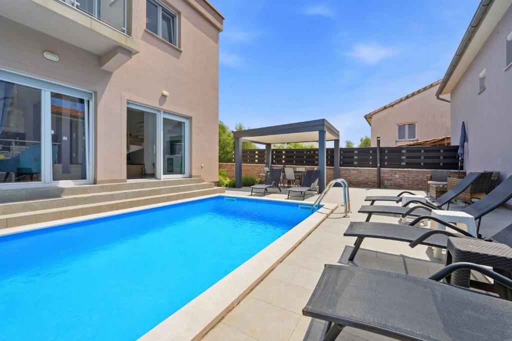 a swimming pool with chairs and a house at House Green in Vrh