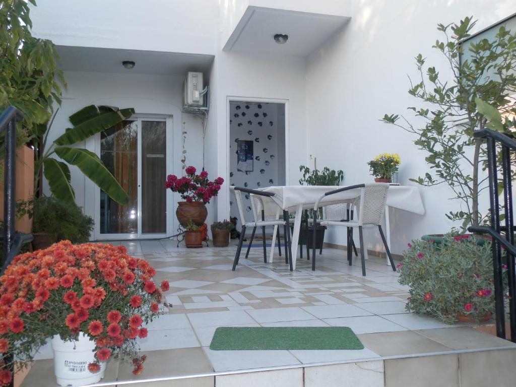 eine Terrasse mit einem Tisch, Stühlen und Blumen in der Unterkunft Silvi Mari Apartments in Platanes