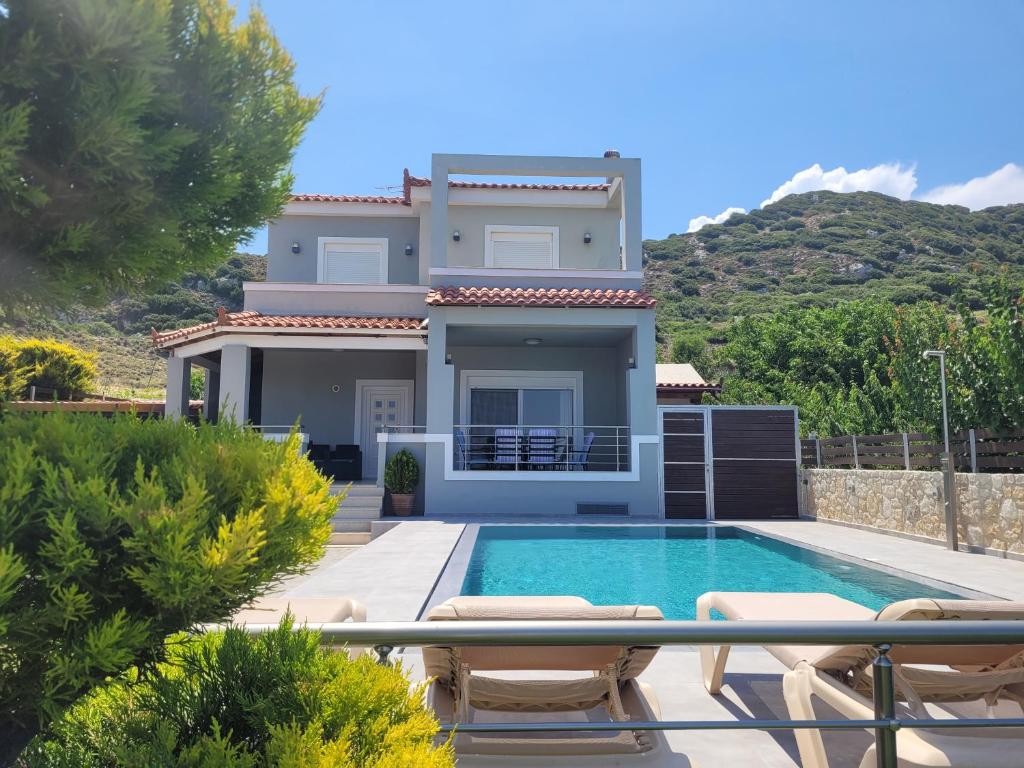 a villa with a swimming pool in front of a house at Luxury Villa Stironas private pool Central Crete in Stíronas