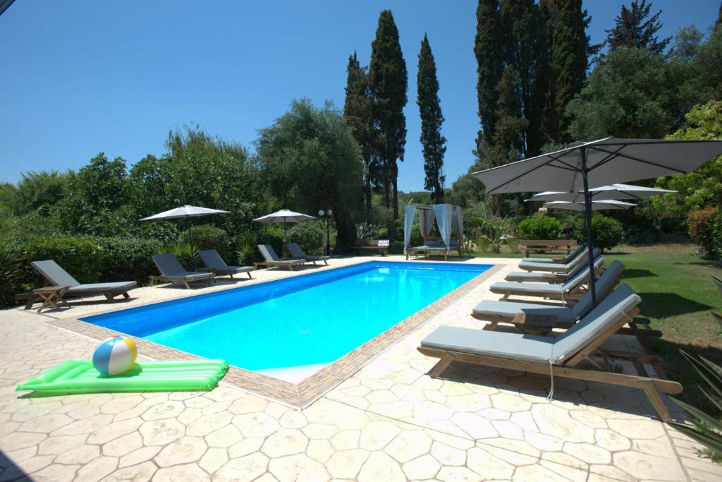 a swimming pool with lounge chairs and umbrellas at Ilias Apartments in Ipsos