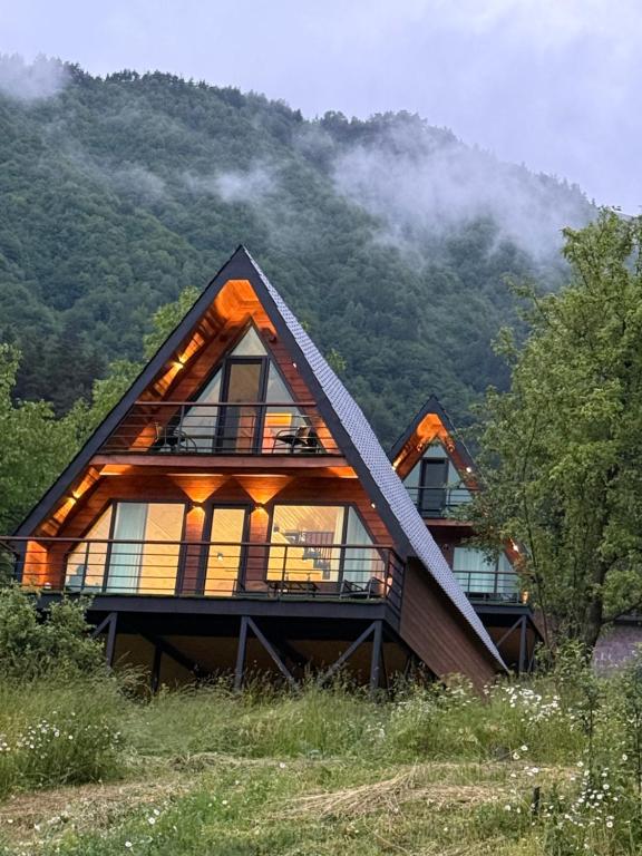 a house with a thatched roof in the mountains at Horizon Mestia - Premium Chalets With Panoramic Views in Mestia