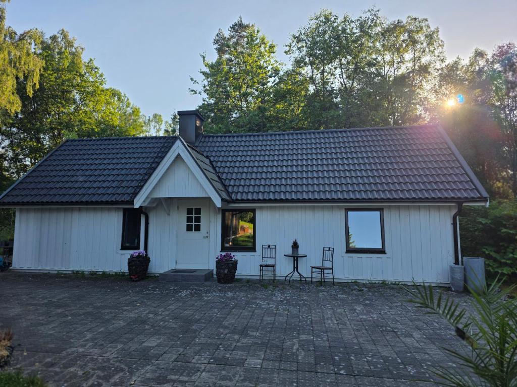 a white house with two chairs and a table at Mysigt hus på 40 kvm i Målaskog in Ryssby