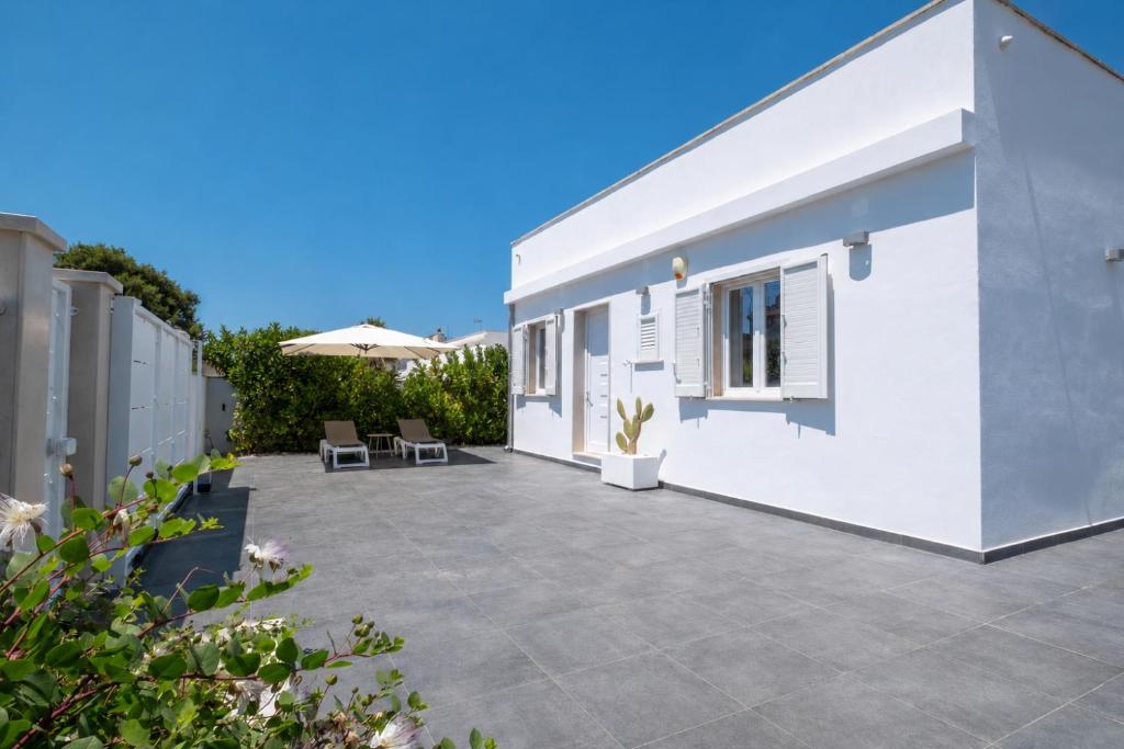 a patio of a white house with chairs and an umbrella at Lu Chiapparu B&B in Nardò