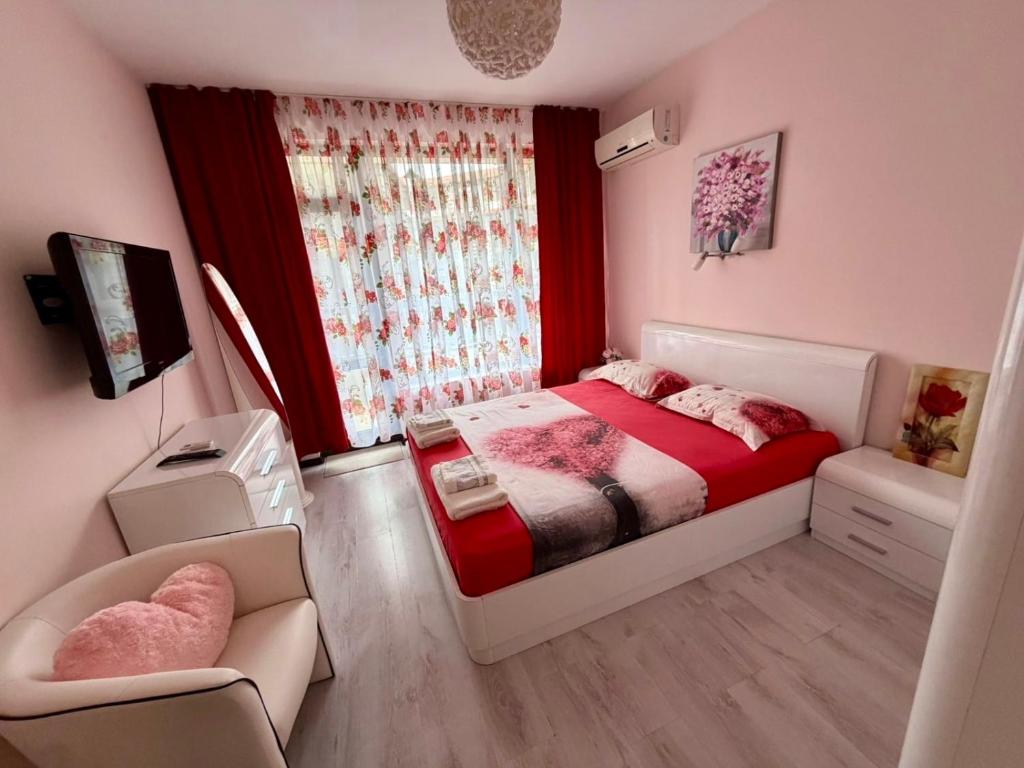 a bedroom with a bed and a chair and a window at Апартамент Green Lines in Primorsko