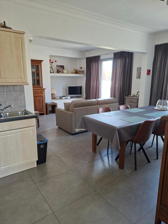 a kitchen and living room with a table and a couch at De Reünie - airconditioned duplex appartement & fietsgarage in Langemark