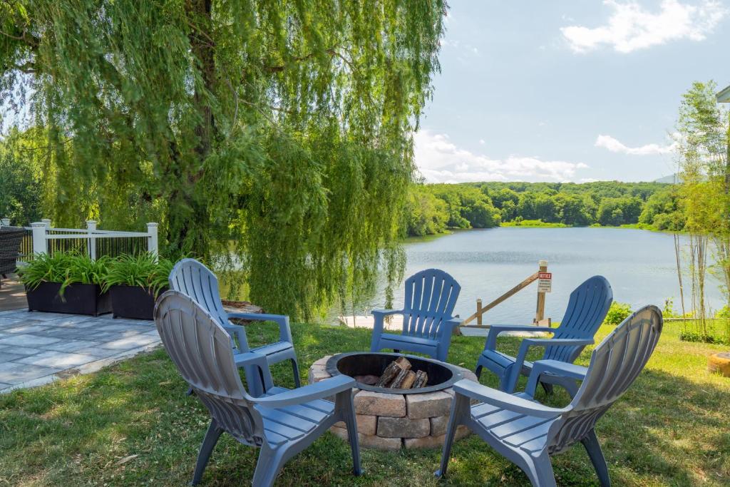 four chairs around a fire pit with a view of a lake at Saugerties Waterfront Getaway in Saugerties