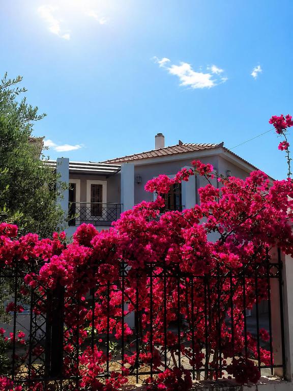 a fence with pink flowers in front of a house at Almyra Seaside Apartments in Elia Laconias
