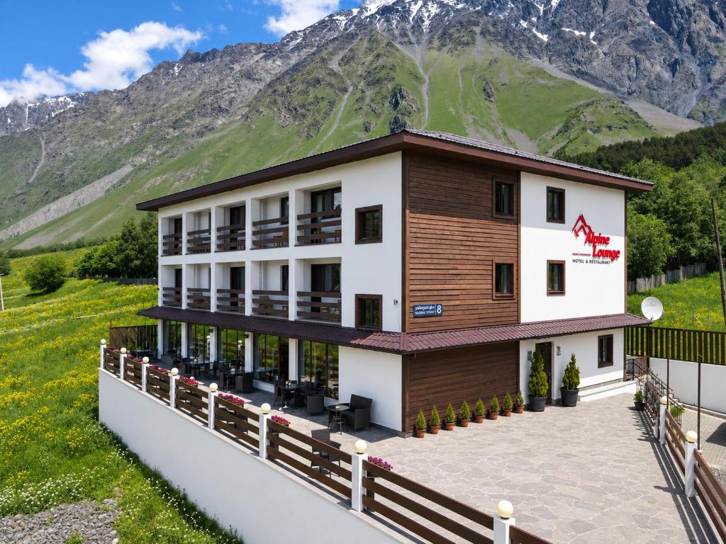 a large building with a mountain in the background at Alpine Lounge Boutique Hotel in Kazbegi